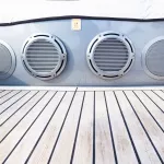 Several music speakers are integrated into the luxury yacht hull. Music speaker integrated into the sofa body on the teak deck of a luxury yacht.