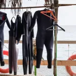 Scuba Diving Wet Suits Hanging to Dry on Rail on Deck of Boat with View of Ocean in Background