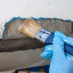 A worker is applying epoxy to polyester pach